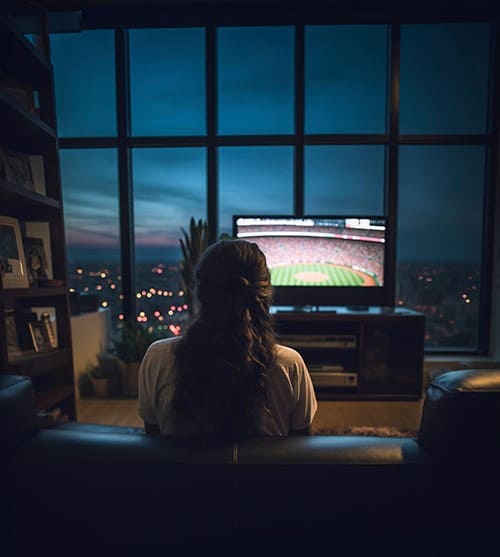 Mulher assistindo TV após a contratação de um dos Planos IPTV